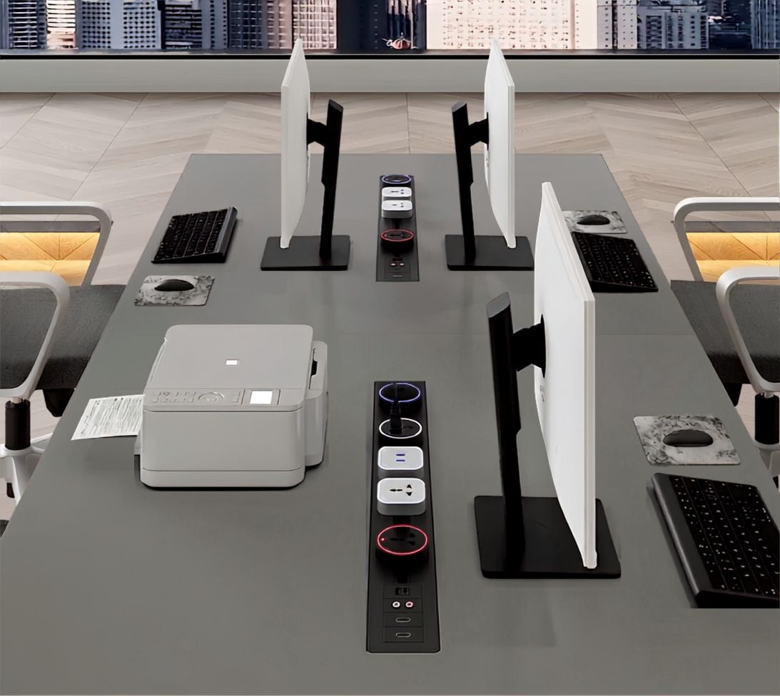Concealed Adivaa Power Tracks with socket modules set into a shared office desk between monitors