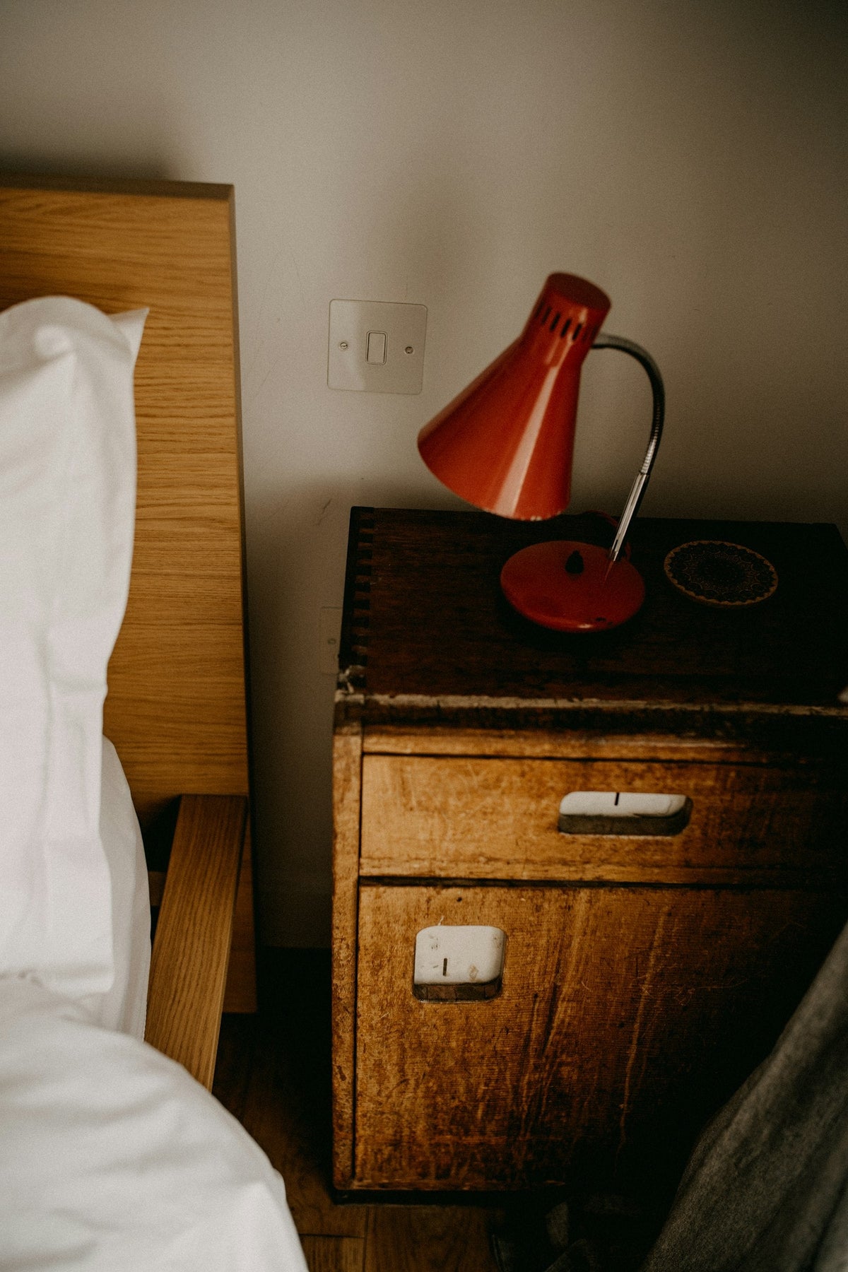 Bedside lamp on a wooden nightstand next to a bed